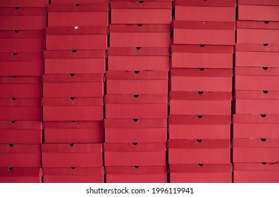 Background of lots of red cardboard package boxes with footwear stacked at a shoe factory warehouse. Business, shoe manufacturing industry, storage, bulk trade, and product distribution concepts