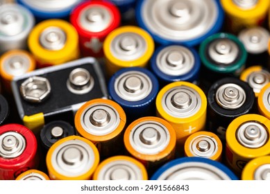 Background made of various alkaline and lithium-ion batteries, positive pole visible.