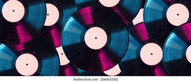 Background of many vintage LP vinyl records in red and blue light.