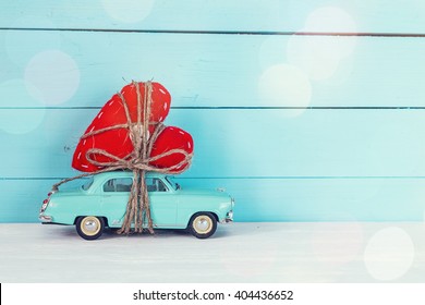 Background with miniature blue toy car carrying a heart on blue painted wooden planks. Place for text. - Powered by Shutterstock