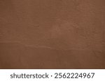 Background of Mocha mousse color of the year 2025 with earthy brown wall bg. Abstract grunge paint wallpaper. Backdrop. Nature. Warm walnut cement wall texture closeup. Mocha Mousse tan smooth surface