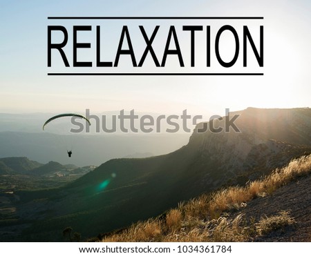 Background of mountain landscape at sunset with person doing paragliding, with the word Relaxation written on top. Concept Advertising.