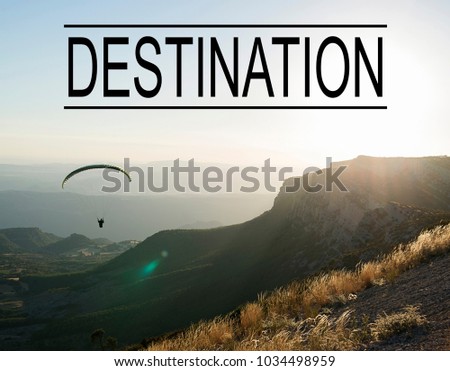 Background of mountain landscape at sunset with person doing paragliding, with the word Destination written above. Concept Advertising.