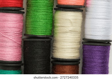 Background of multicolored spools of thread on white background in closeup