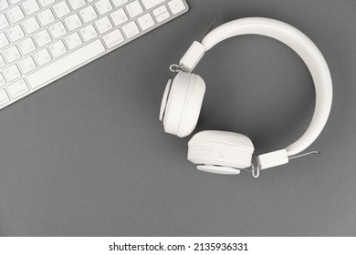 Background music or podcast with headphones and a computer keyboard on a gray table, flat. Top view, flat layout