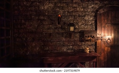 Background of mystical dark interior of medieval room with large wooden door and skull on table against an ancient stone wall. Amazing backgrounds for Halloween holiday. Copy space, text place - Shutterstock ID 2197319879