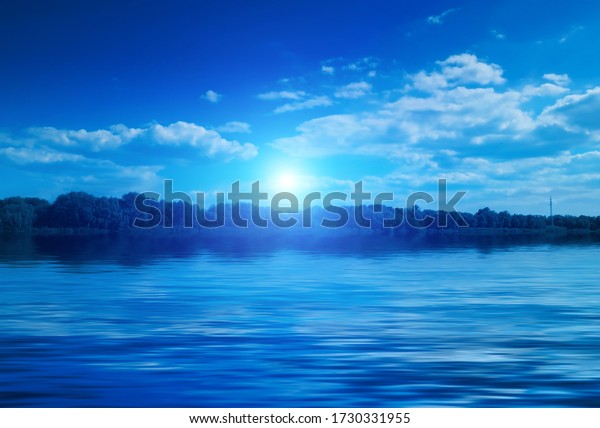 Background of night sea landscape.\
Night sky, clouds, full moon. Reflection of the moon on the water.\
Sunset on the sea horizon. Blue tinted blurred\
background.
