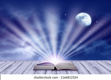 Background Of Night Sky With Mysterious Clouds, Moon, Stars And Open Fairytale Book And Rays Shining From It On Table In Shabby Chic Style. Moon Is Taken By Me With My Camera.