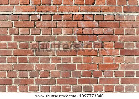 Background of old red brick wall with scratches, holes and gaps