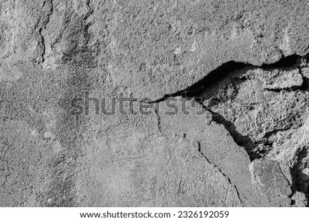 Background of old wall with collapsed plaster. Texture of shabby weathered building surface. Destroyed wall with fallen plaster. Copy space. Black and white photo. Selective focus.