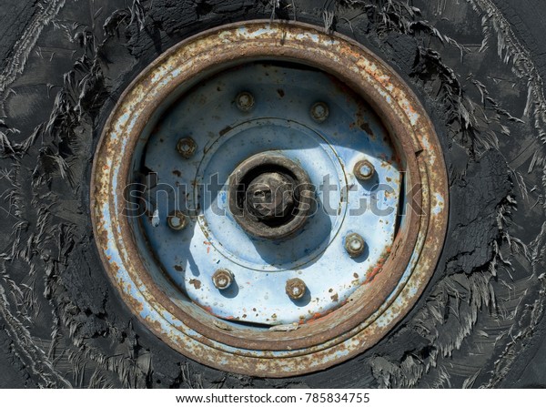 background: old wheel of auto, worn out tire,\
discolored, broken, resting outdoors, full of weathered cracks,\
broken filaments, blue iron rim rusted by weather, dangerous for\
road safety, black,\
Italy