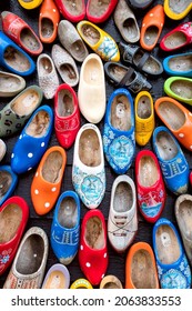 Background - Old wooden Dutch shoes - klomps. A lot of colorful old clomps against the background of a wooden wall. Popular souvenirs. Traditions of Holland. 