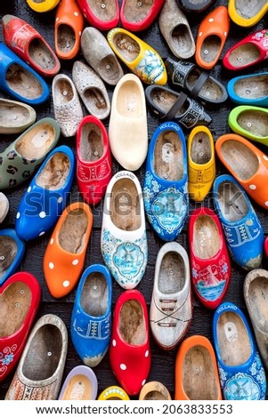 Background - Old wooden Dutch shoes - klomps. A lot of colorful old clomps against the background of a wooden wall. Popular souvenirs. Traditions of Holland. 