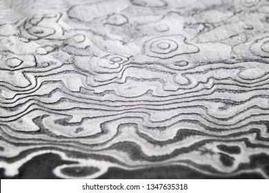 Background with pattern of damask steel. Close up. Macro shot of a damascus knife blade texture. Damascus steel pattern. Metal and steel background. Damascus steel with original pattern. 