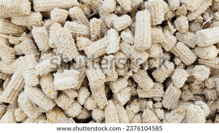 The background is patterned with piles of yellowish white corncobs