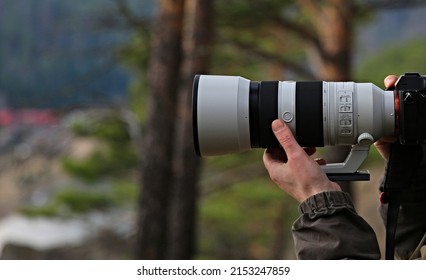 Background Photographer With A White Long Telephoto Lens Shoots