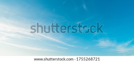 Background picture low angle of bright blue sky on a sunny day. There are fluffy white clouds and clear. Blue and white color contrast in soft tones. Feeling fresh and relax. There is a copy space.