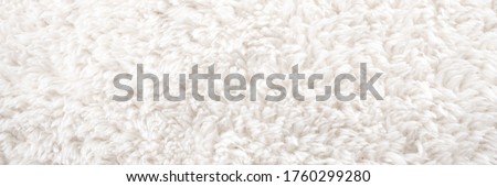 Background picture of a soft fur white carpet. wool sheep fleece closeup texture background. Fake color beige fur fabric. top view.  banner size. panorama. ,panoramic.