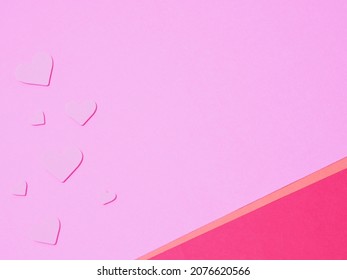 A Background Of Pink Construction Paper With Hearts Of The Same Color Scattered Around.