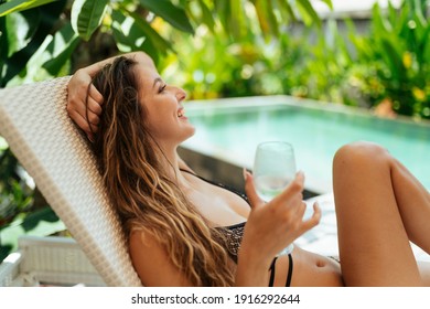 In the background of the pool with a glass in hand the girl in the shizong laughs cheerfully and joyfully. High quality photo