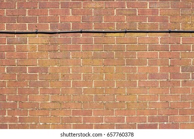 Background of red brick wall pattern with a black cable