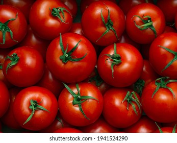 Background of red ripe liquid tomatoes with green leaves in full screen. Texture of oriental greenhouse large vegetables in market, store. Close-up, top view, food wallpaper.  Concept of harvesting. - Powered by Shutterstock