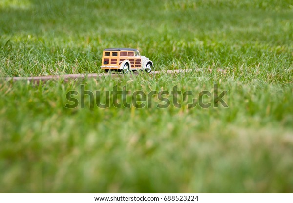 Background with retro toy car.
Beautiful toy car rides through the field. Travel and
transportation concept. Car insurance. Summer vacations. Traveling
by car.