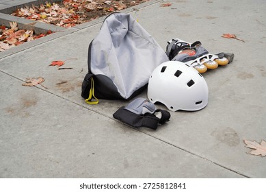 Background with rollerskate protective gears, rollerblade, helmet and knee pads outdoors in autumn