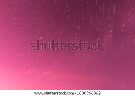 Background of round or circular star track or trajectory on the red, pink or rose clear night sky. Symbol of space, cosmos, expanse infinity and universe