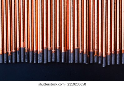 A background of round graphite gouging electrodes stacked vertically together. New copper straight rods.