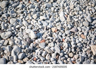 Background from sea pebbles on the beach, close-up. Small and big roundish smooth stones. Texture of beach pebbles for a post, screensaver, wallpaper, postcard, poster, banner, cover, website