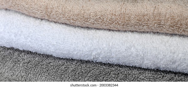 The Background Is A Set Of Terry Cotton Towels Gray Beige White.