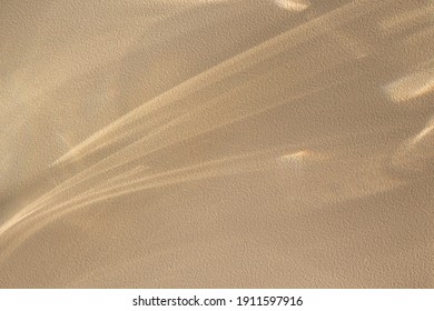 Background with shining lines of natural light on a sand color textured wall.Minimal summer concept with shadows on the wall.Creative copyspace for overlay on product presentation,backdrop and mockup.