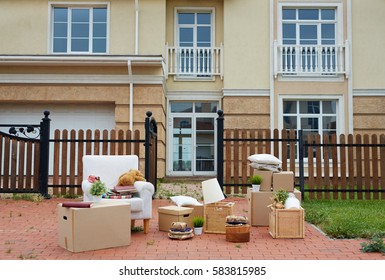 Background Shot In Creme Tones Of Cardboard Boxes And Furniture Outside, On Lawn In Front Of Expensive House, Ready To Be Moved In