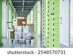 Background shot of dolly cart loaded with cardboard boxes storing personal belongings in hallway of self storage warehouse during moving out or apartment decluttering, copy space