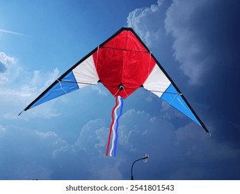 The background is the sky with some white clouds. In the picture are three square-shaped kites in blue, white, and red. There are three to four strings hanging down. They are used for flying kites 