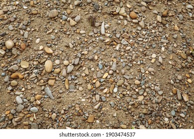 Background from  stones. Gravel texture. Small and medium stones, pebbles of many shades of gray, white, brown, yellow, mixed with sand. The texture of small stones for paving the road.
