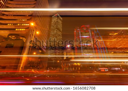 Background of street traffic and skyscaper building with long tail light foreground at Hong Kong central