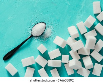 background of sugar cubes and sugar in spoon. White sugar on turquoise background. Sugar with copy space. Top view or flat lay