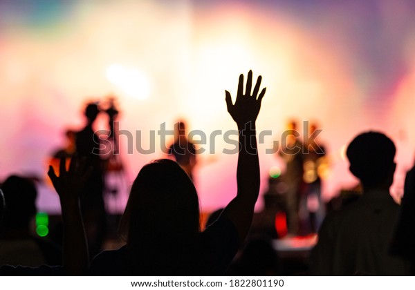Background of Sunday service in church:\
Blurred silhouette woman raised hand to worship\
God
