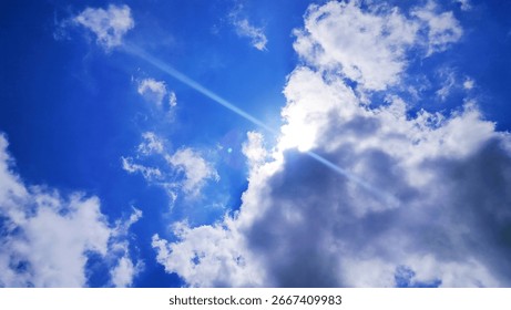 Background of sunlight through the clouds with a blue sky behind. Blue sky with clouds.one of the clouds partially covers the sun, a ray of sunlight breaks through because of a cloud