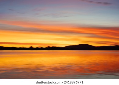 Background sunset intentional camera movement effect bright orange hues on morning light blue hour. over Waimapu Estuary in Tauranga New Zealand.