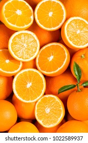 Background from sweet fresh whole and halves of orange fruits with green leaves.