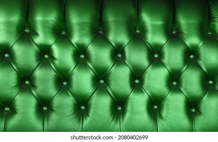 Background texture of dark emerald green capitone genuine leather, retro Chesterfield style soft tufted furniture upholstery with deep diamond pattern and buttons, close up