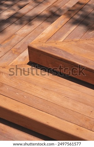 Background texture of hardwood steps of elevated walkway in public park area with sunlight and tree branch shadow on surface, high angle view and vertical frame