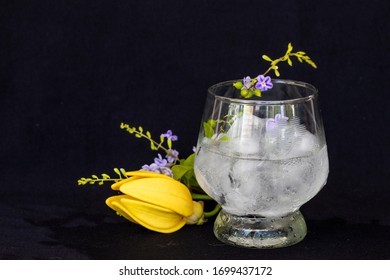 Background Texture Iced ,water In Glass With Purple Flower, Yellow Flowers Ylang Ylang Decoration Postcard Style On Black