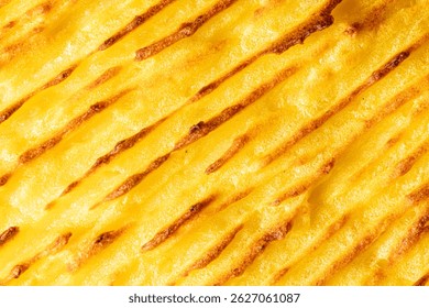 A background with the texture of mashed potatoes baked until golden brown in the oven. Close-up, macro photography. Use for menu and banner. High quality photo