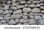 A background texture of natural large solid gray boulders, a full frame, a fragment of a stone fence or wall made of gray rock in the form of rough pieces and blocks