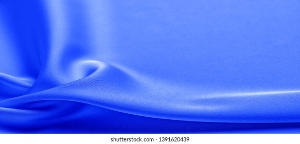 background texture, pattern. blue silk fabric. This lightweight fabric has a brilliant shine that perfectly reflects the light and crumpled texture that adds interest and depth to any fabric design.