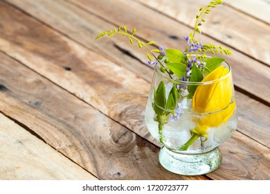 Background Texture Purple Flower ,yellow Flower Ylang Ylang And Iced Water In Glass Arrangement Flat Lay Postcard Style On Wooden